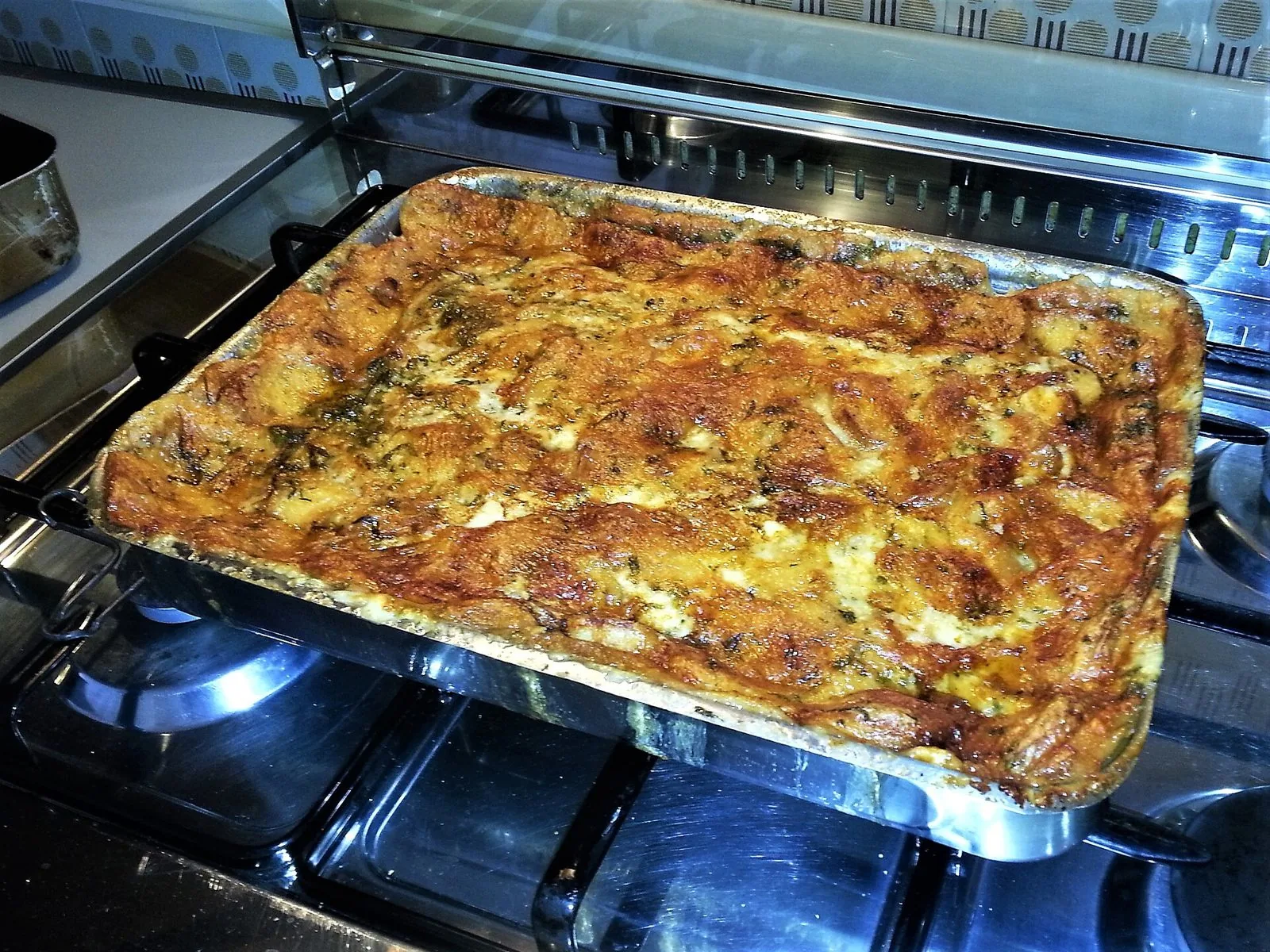 Teglia di zuppa gallurese appena sfornata con superficie dorata e croccante